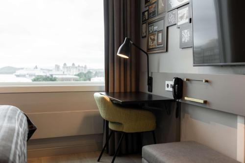a room with a desk with a lamp and a window at Scandic Byporten in Oslo