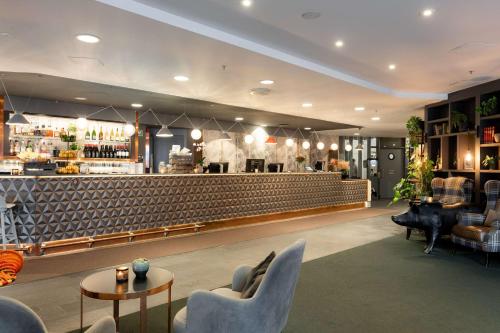 a lobby with a bar with chairs and a piano at Scandic Byporten in Oslo