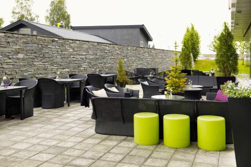a patio with tables and chairs and a stone wall at Scandic Oslo Airport in Gardermoen
