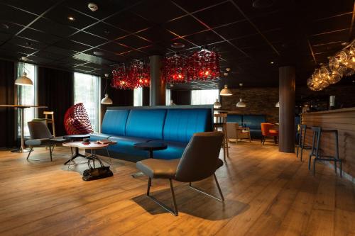 a room with a blue couch and chairs and tables at Scandic Stavanger City in Stavanger
