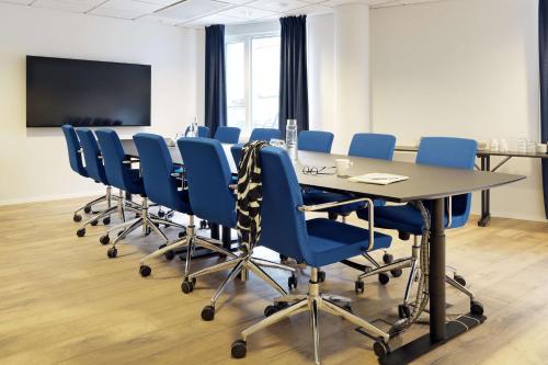 a conference room with a long table and blue chairs at Scandic Stavanger City in Stavanger