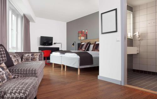 a bedroom with a bed and a couch and a tv at Scandic Stavanger Forus in Stavanger