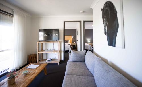 a living room with a couch and a tv at Harkham Lodge in Pokolbin