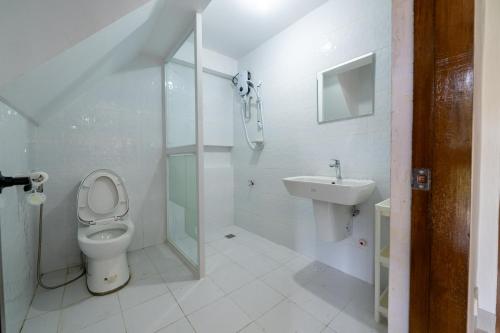 a white bathroom with a toilet and a sink at The Warehouse Loft in Baguio