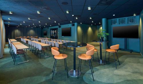une salle de conférence avec des tables, des chaises et un écran dans l'établissement Scandic Bollnäs, à Bollnäs