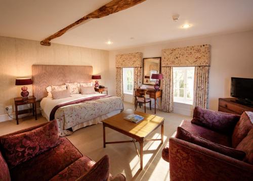 a bedroom with a bed and a couch and a table at Hintlesham Hall Hotel in Ipswich