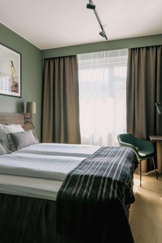 a bedroom with a bed and a chair and a window at Scandic Rubinen in Gothenburg