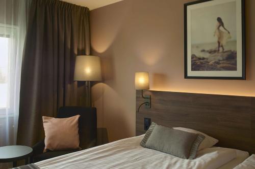 a hotel room with a bed and a chair and a window at Scandic CH in Gävle
