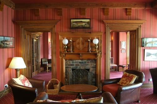a living room with a fireplace and leather chairs at Lake Vyrnwy Hotel & Spa in Llanwddyn