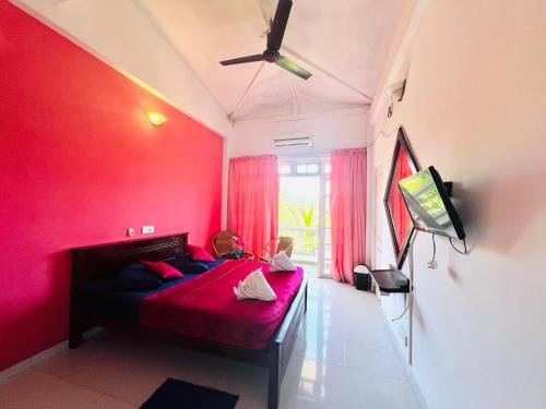 a child sitting on a bed in a room with pink walls at New Blue Mount View Kandy in Kandy