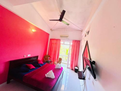 a child sitting on a bed in a room with pink walls at New Blue Mount View Kandy in Kandy