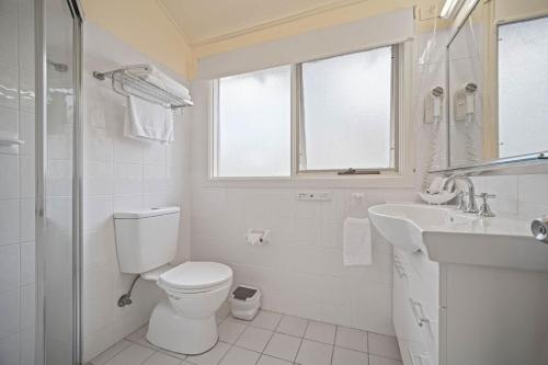 a white bathroom with a toilet and a sink at Shores Beach & Lakeside Villas in Elizabeth Beach