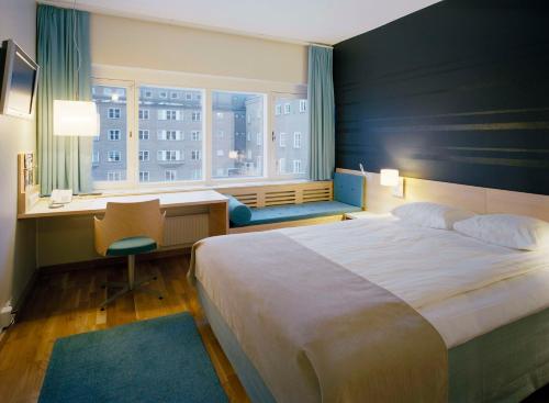 a bedroom with a large bed and a desk and a window at Scandic Frimurarehotellet in Linköping