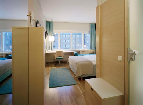 a hotel room with a bed and a desk and a room at Scandic Frimurarehotellet in Linköping