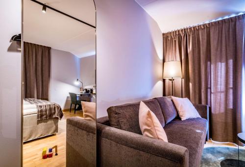a living room with a couch and a mirror at Scandic Frimurarehotellet in Linköping