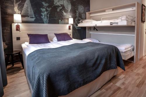 a bedroom with a large bed with purple pillows at Scandic Linköping Väst in Linköping