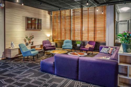a lobby with purple couches and chairs in a room at Scandic Linköping Väst in Linköping