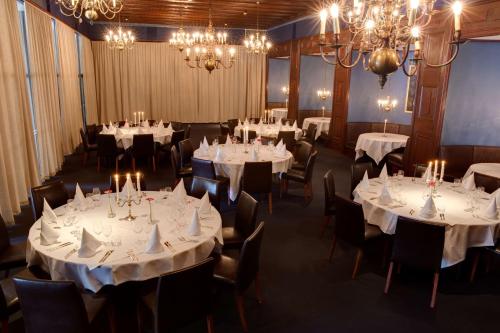 a dining room with white tables and chairs and chandeliers at Scandic Frimurarehotellet in Linköping