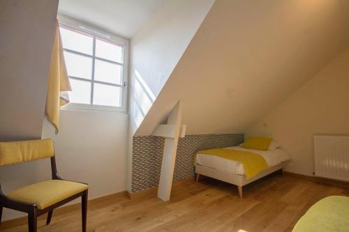 a room with a bed and a chair in a attic at L'oree des mers in Guidel