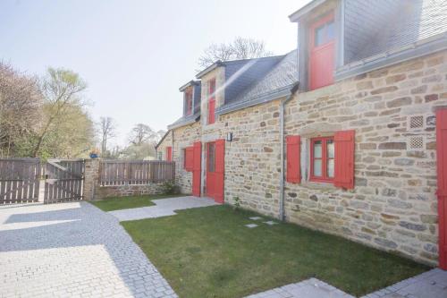 a brick house with red doors and a yard at L'oree des mers in Guidel
