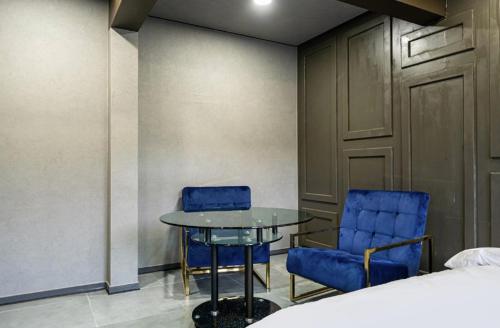 a room with two blue chairs and a table and a bed at Moonstay Hotel Cheonan in Cheonan