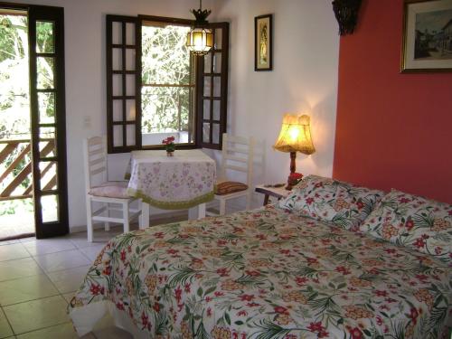 1 dormitorio con 1 cama, mesa y sillas en Vila São Pedro, en Ilhabela