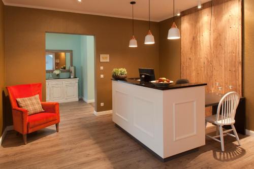 a kitchen with a counter and a red chair at Dorint Resort Baltic Hills Usedom in Korswandt