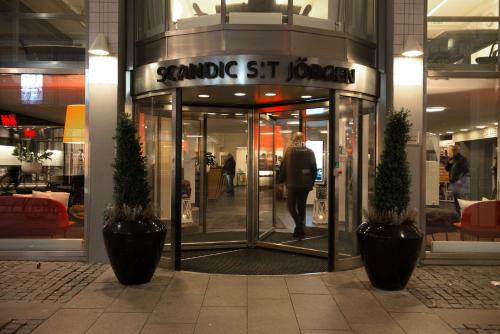 a man walking into a store with a revolving door at Scandic S:t Jörgen in Malmö
