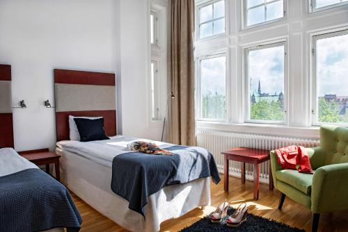 a bedroom with a bed and a chair and windows at Scandic Stortorget in Malmö