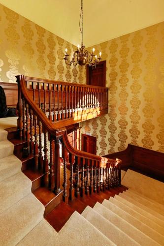 a wooden staircase in a room with a chandelier at Hintlesham Hall Hotel in Ipswich