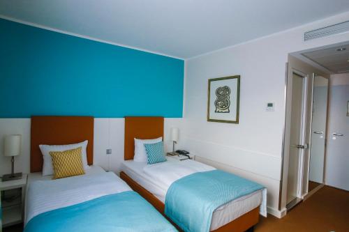 two beds in a room with blue and white at Congress Hotel am Stadtpark in Hannover