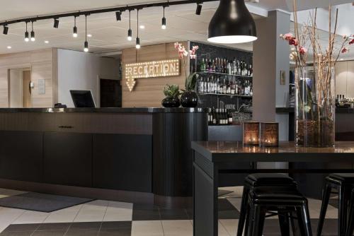a bar with a black counter and stools at Scandic Norrköping Nord in Norrköping