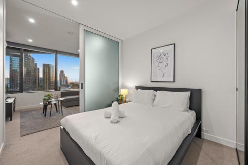 a bedroom with a large white bed and a large window at Restful CBD Park Views Retreat in Melbourne