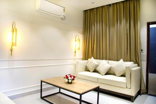 a living room with a white couch and a table at Hunkal Stays in Chikmagalūr