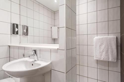 Baño blanco con lavabo y espejo en Ramada London Stansted Airport, en Stansted Mountfitchet