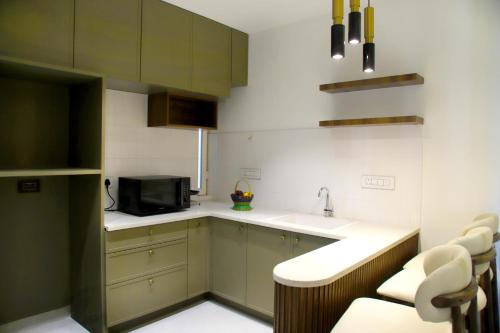 a kitchen with green cabinets and a sink and a microwave at Hunkal Stays in Chikmagalūr