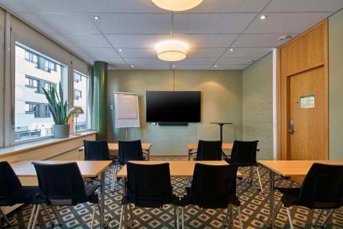 a conference room with tables and chairs and a flat screen tv at Scandic Skellefteå in Skellefteå