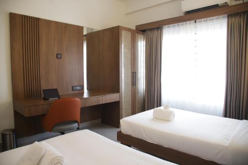a hotel room with two beds and a desk at Hunkal Stays in Chikmagalūr