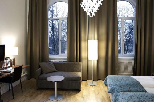 a hotel room with a bed and a couch and a desk at Scandic Billingen in Skövde