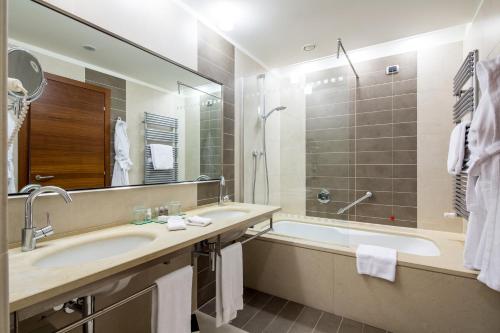 a bathroom with a sink and a tub and a mirror at Best Western Premier BHR Treviso Hotel in Quinto di Treviso
