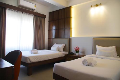 a hotel room with two beds and a window at Hunkal Stays in Chikmagalūr