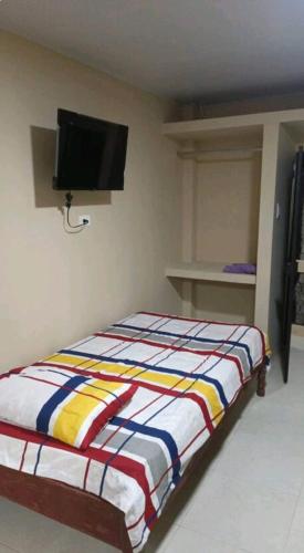a bedroom with a bed with a tv on the wall at Cuarto Monoambiente Pucem in Portoviejo