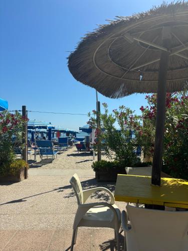 a table and chair with an umbrella on the beach at Long Beach Village Residence sul mare spiaggia privata inclusa in Lido Adriano