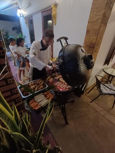 a man cooking food on a grill in a room at Meyers Hua Hin in Hua Hin