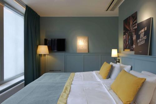 a bedroom with a bed with yellow pillows and a television at Scandic Grand Central in Stockholm