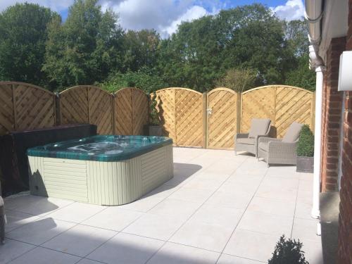 a hot tub on a patio with a fence at Hintlesham Hall Hotel in Ipswich