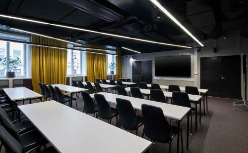 a conference room with tables and chairs and a tv at Scandic Grand Central in Stockholm