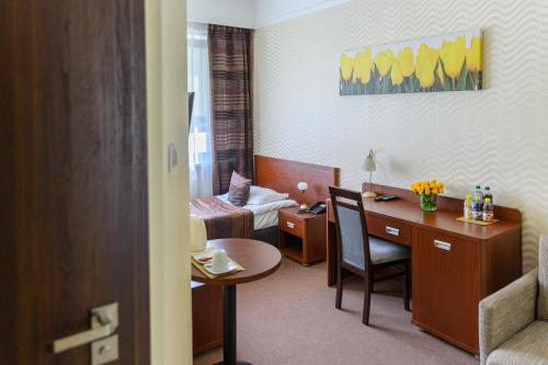 a hotel room with a desk and a bedroom at Hotel & SPA Odeon in Boguchwała