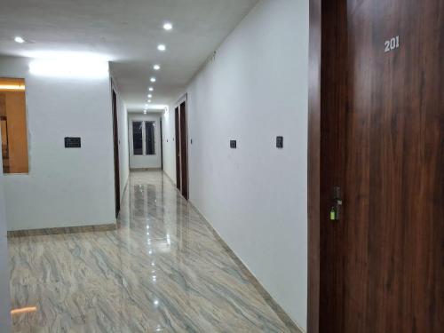 an empty hallway with white walls and a wooden door at Hotel Surya Inn in Kānsrao