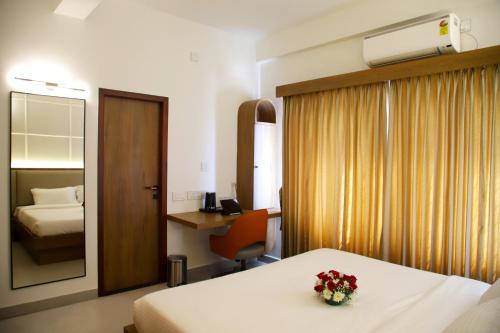 a hotel room with a bed and a desk and a mirror at Hunkal Stays in Chikmagalūr